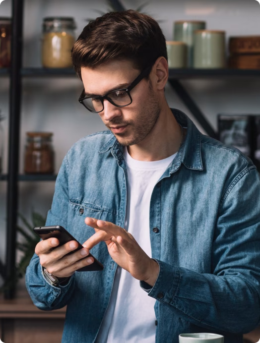 Homem de óculos digitando no celular