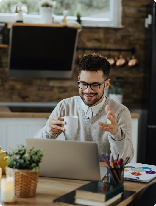 Homem sorrindo em frente ao notebook na cozinha